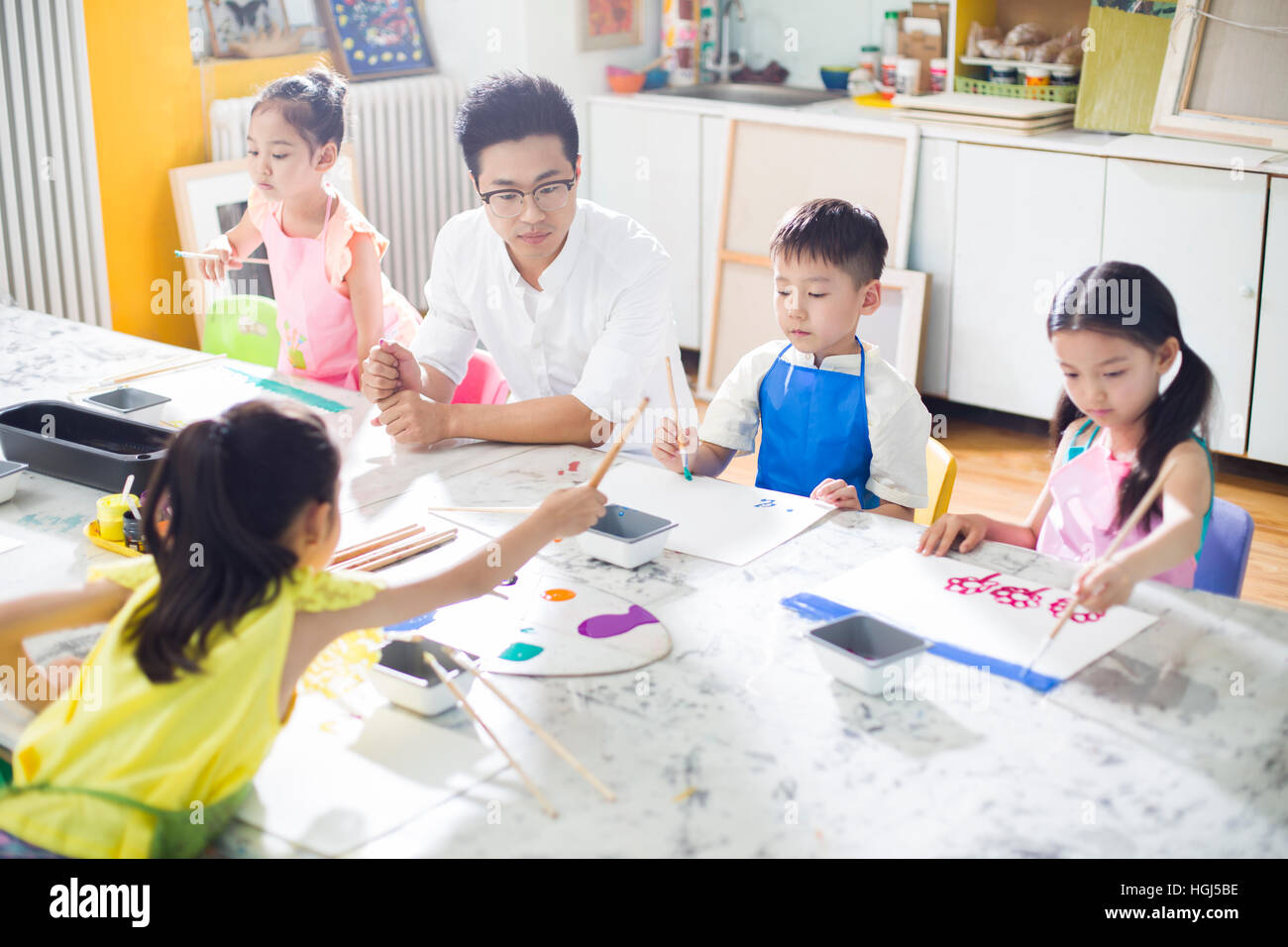 Little children painting in art class with teacher Stock Photo - Alamy