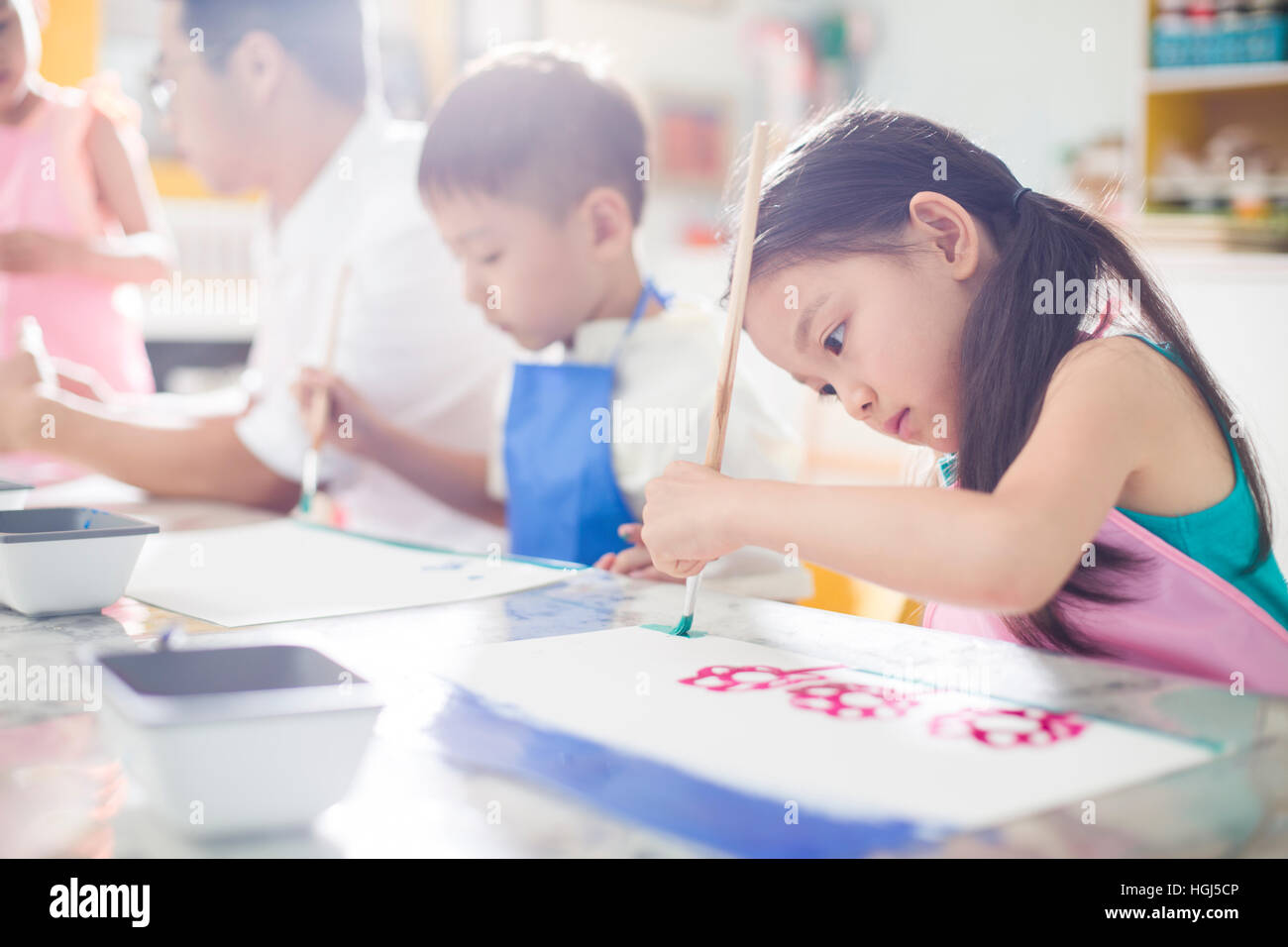 Little children painting in art class with teacher Stock Photo - Alamy
