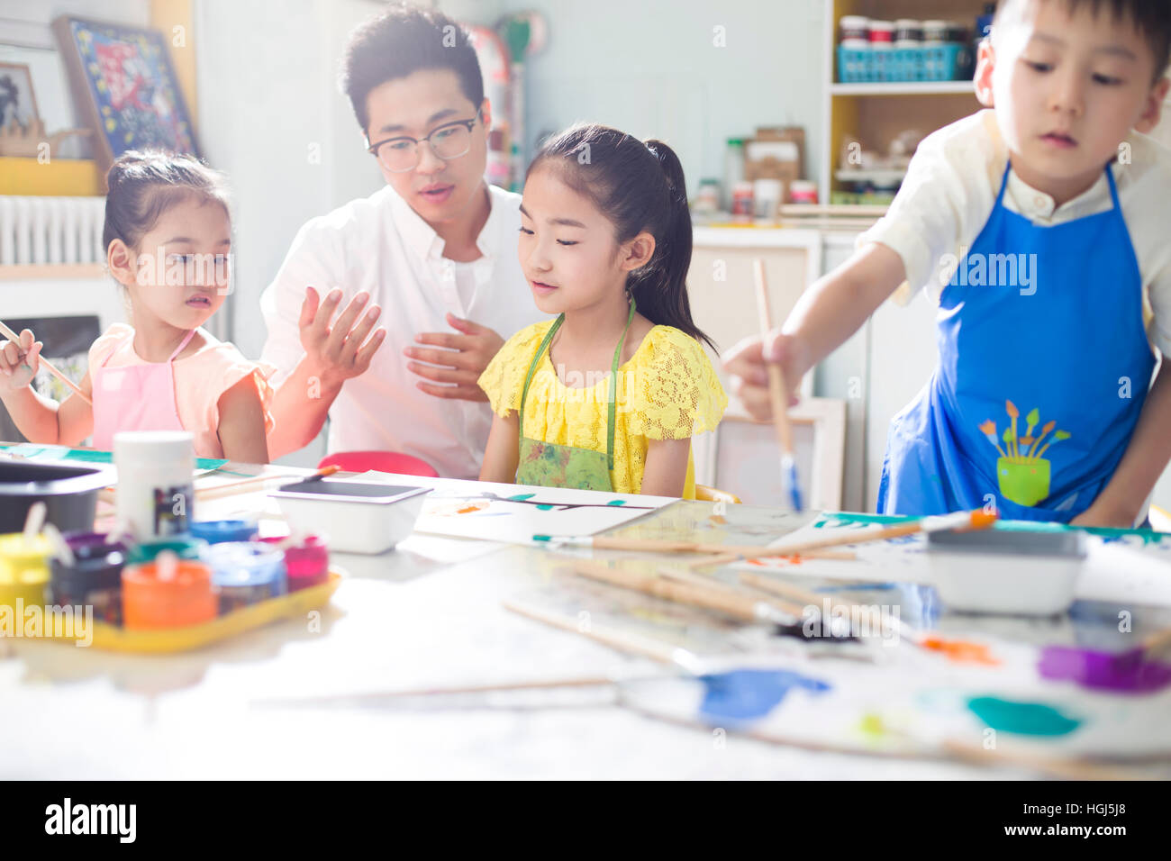 Little children painting in art class with teacher Stock Photo - Alamy