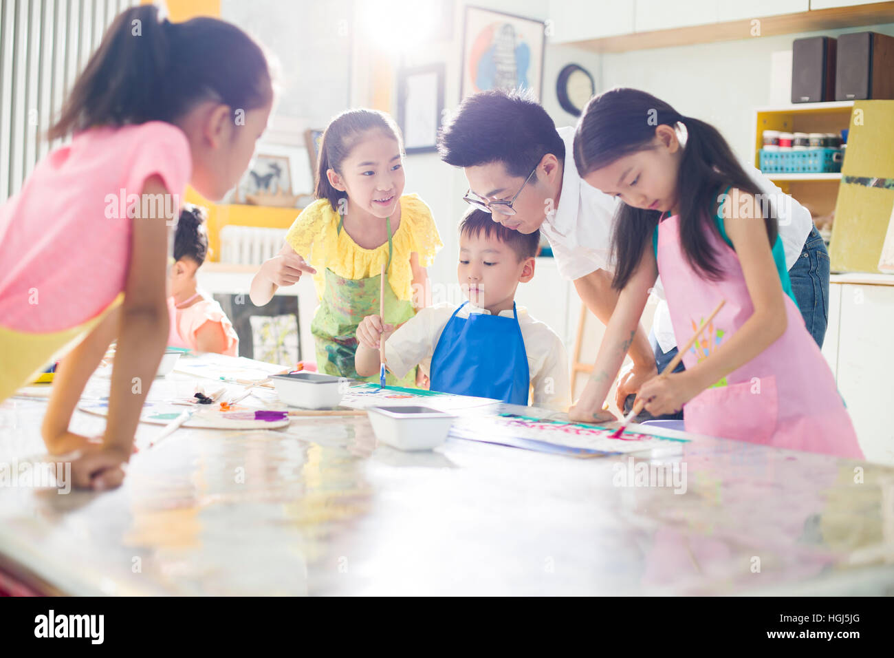 Little children painting in art class with teacher Stock Photo - Alamy