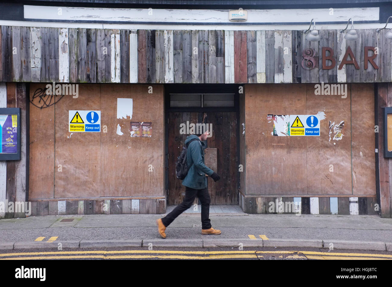 A man walking past a closed business in Falmouth, Cornwall, UK Stock Photo
