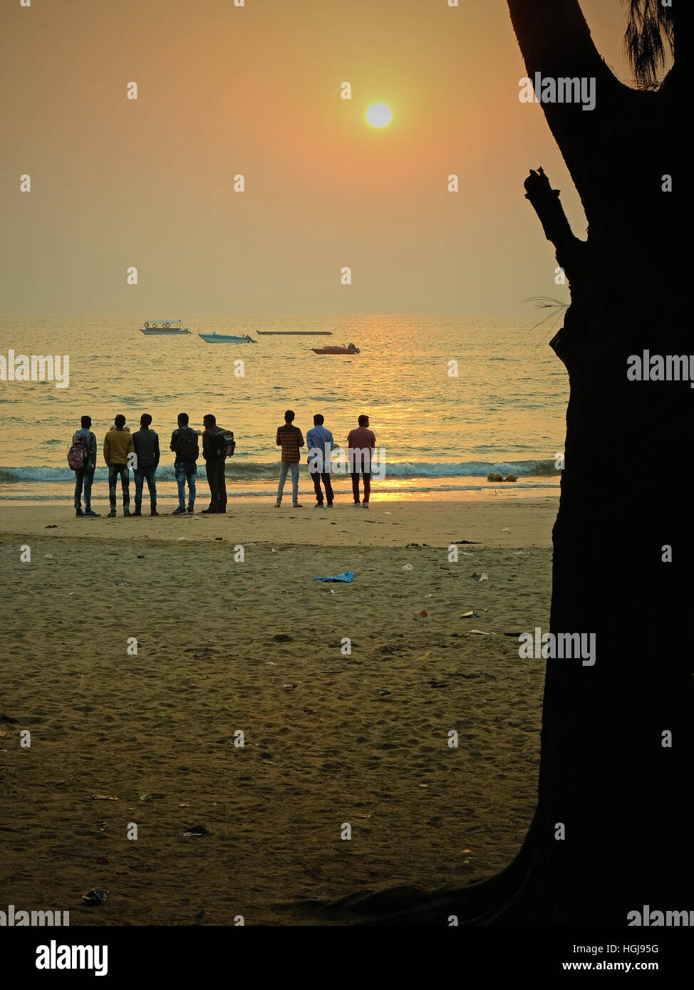 Young people watching the sunrise over the Arabian Sea on Nagao Beach on Diu Island in the state of Gujarat Stock Photo