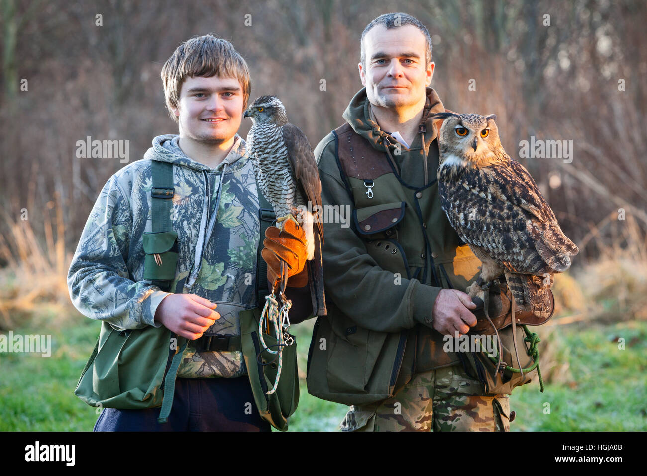 Two falconers in the countryside with their birds of prey, a Goshawk and a Eurasian Eagle Owl. UK. Stock Photo