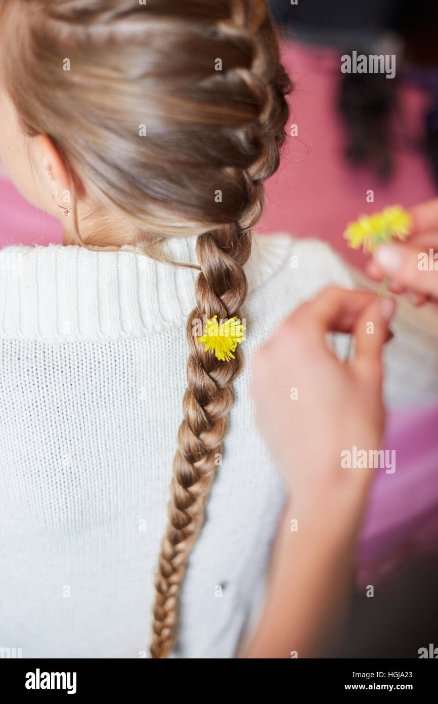 young girl with flowers in her pigtail hair. Vertical shot Stock Photo