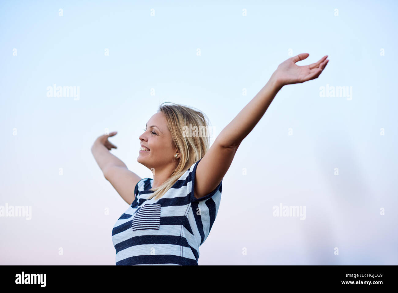 Young woman raising her arms to embrace the sky Stock Photo - Alamy