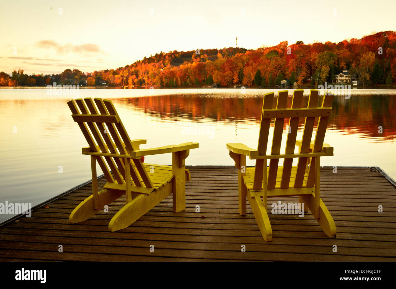 Two yellow Adirondack Muskoka chairs on a dock in the evening