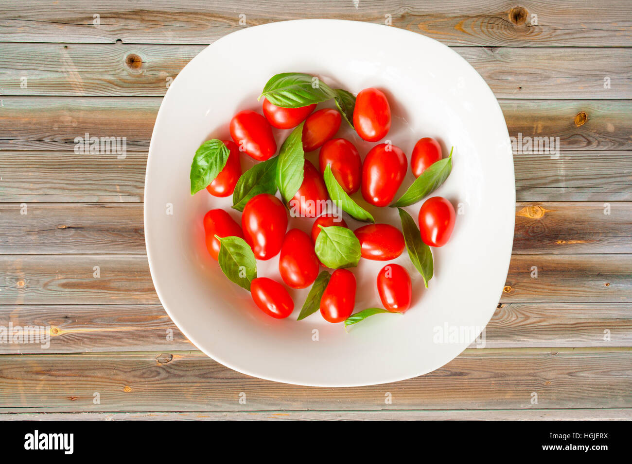 Fresh grape tomatoes and basil leaves in white bowl Stock Photo - Alamy