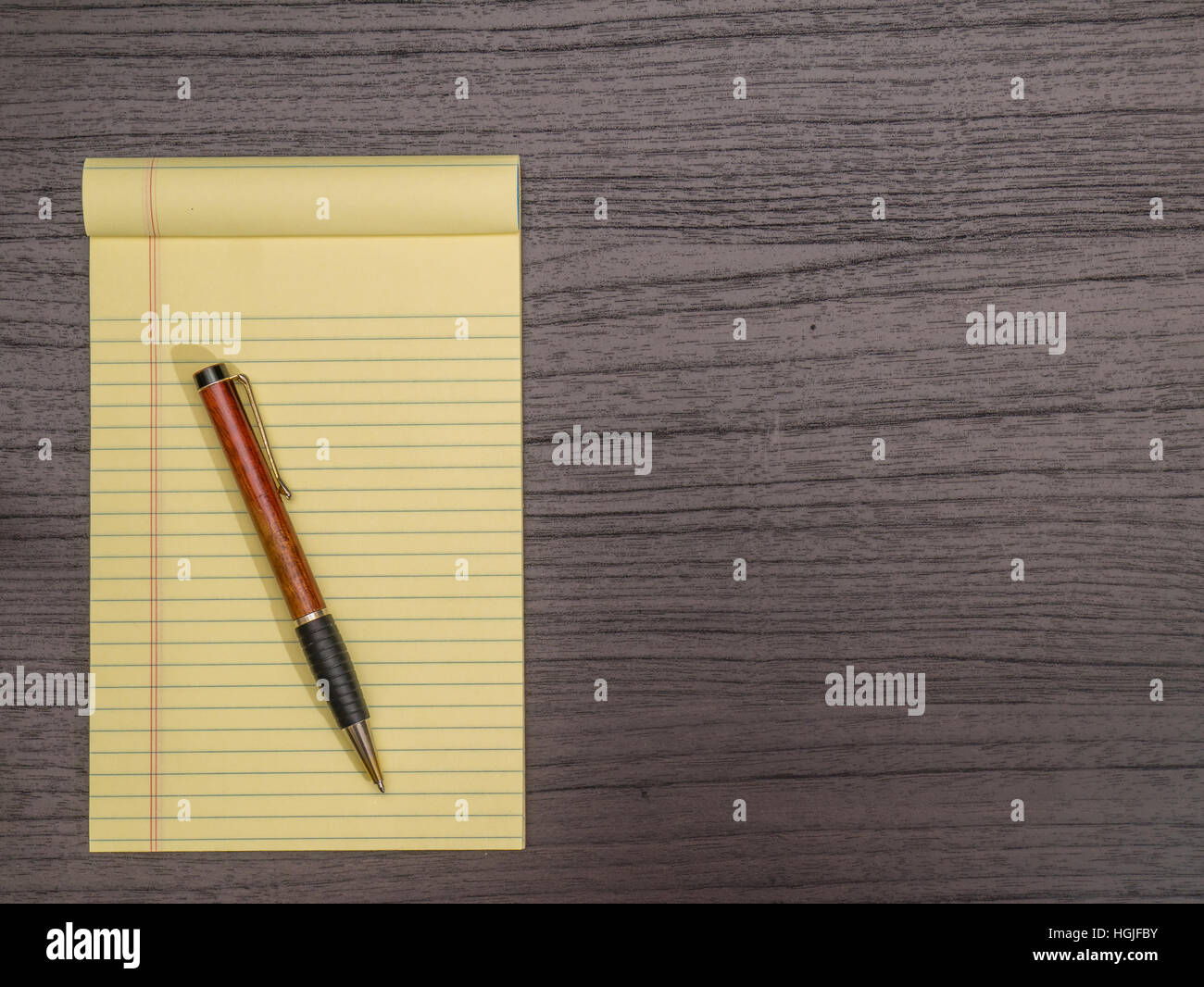 Dark Wood Desk, Yellow Pad, Pen on Pad Stock Photo