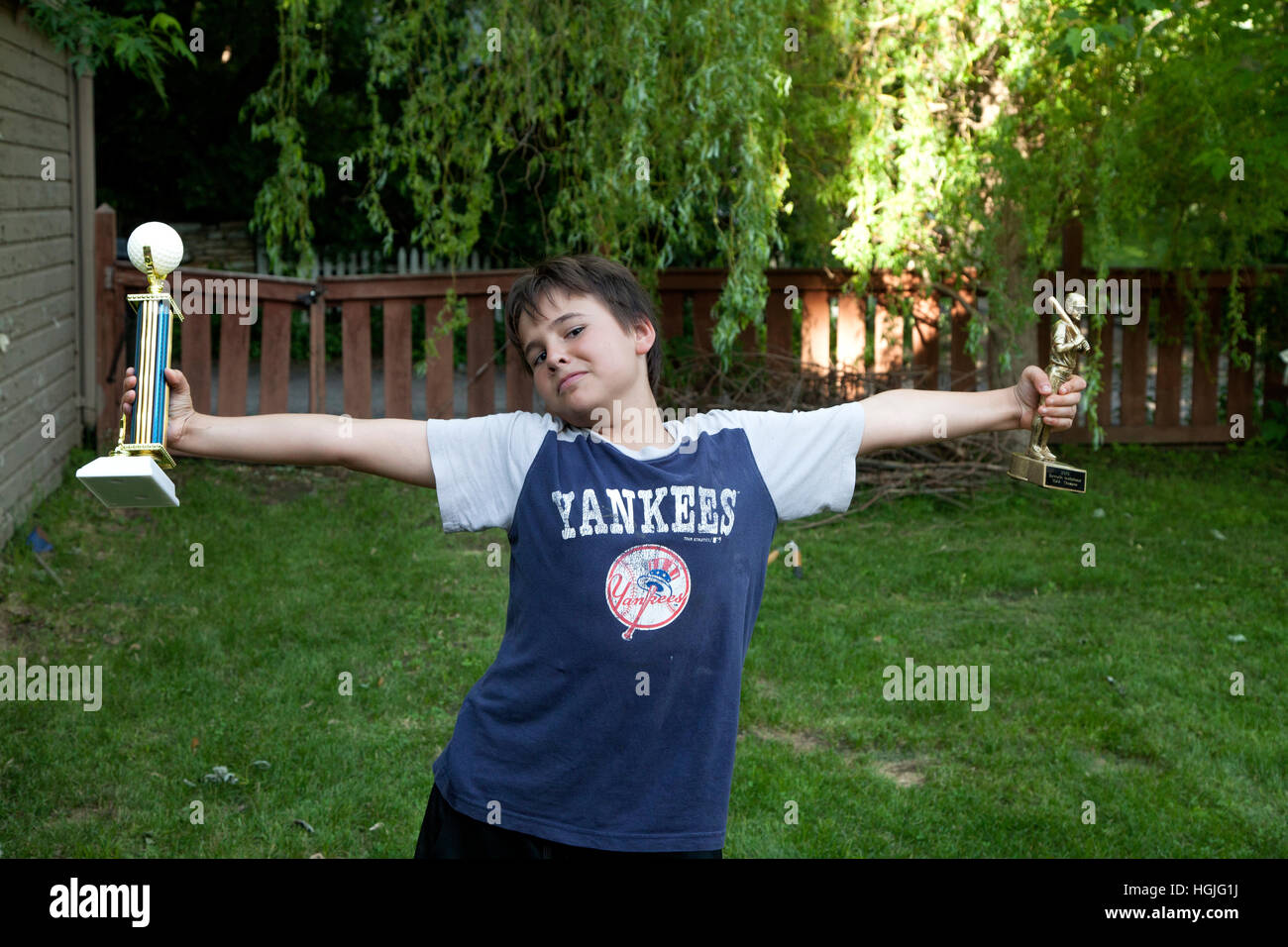 My grandson age 11 exhibits his golf and baseball trophies with exuberance. St Paul Minnesota MN USA Stock Photo