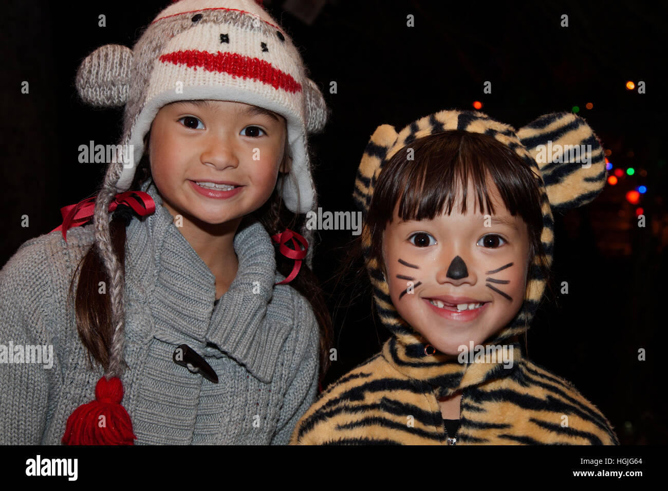 Two bright eyed young Asian American girls in a monkey cap and tiger Halloween costume trick or treat. St Paul Minnesota MN USA Stock Photo