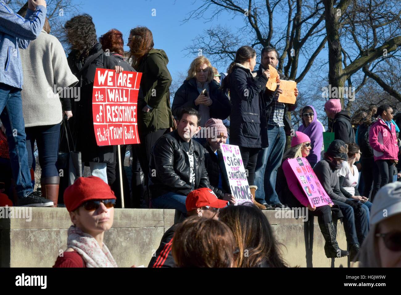 Men and Women protesters carrying signs and sitting and standing on a wall during the 2017 Chicago Woman's March Stock Photo