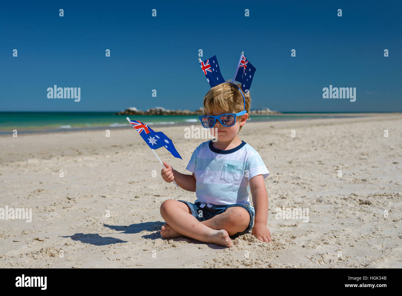 Cute smiling kid with flags of Australia sitting on the sand at the ...