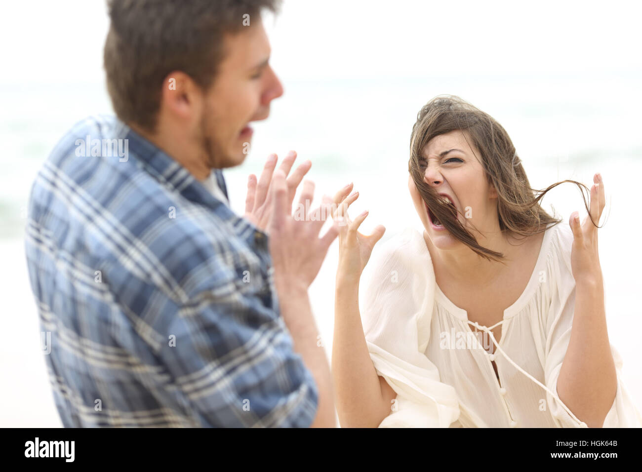 Ugly and crazy woman shouting to her scared boyfriend outdoors on the beach Stock Photo
