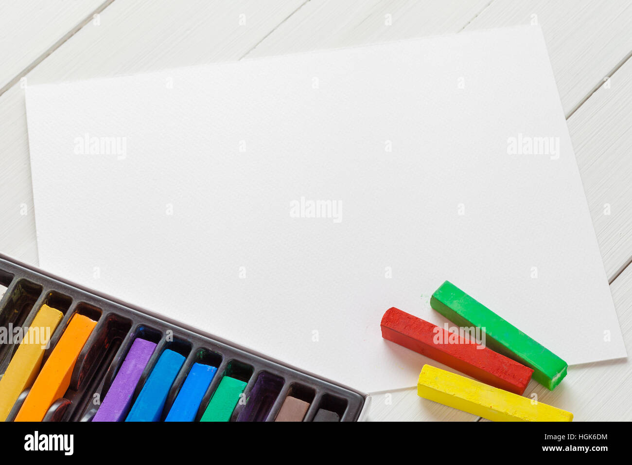 Watercolor pastel crayons and white paper sheet of sketchbook on white