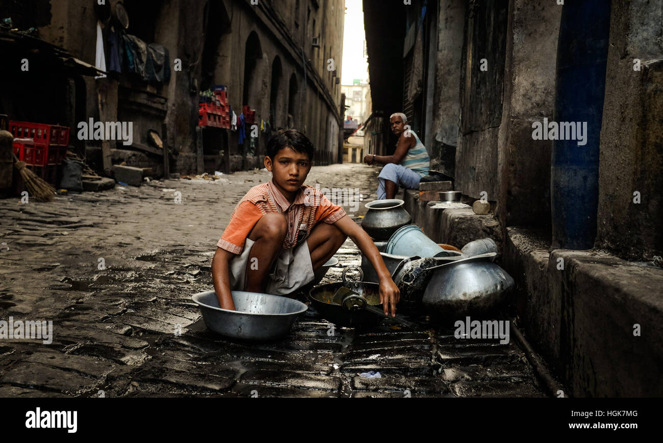 A boy doing the washing in the back alley of the Kolkata slums. Stock Photo
