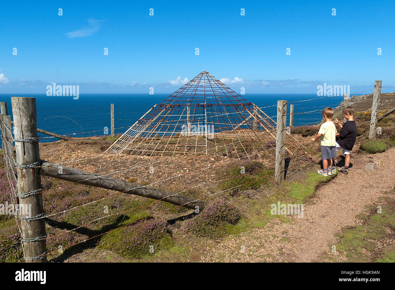 Two children looking at a capped tin mine shaft on the coast of Cornwall, England, UK Stock Photo