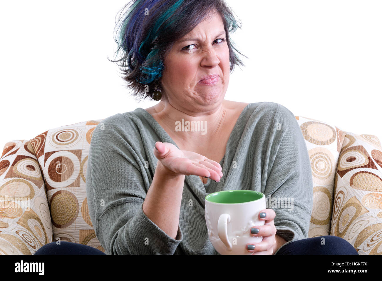 Disgusted woman in chair gesturing with hand to cup of tea, white background Stock Photo