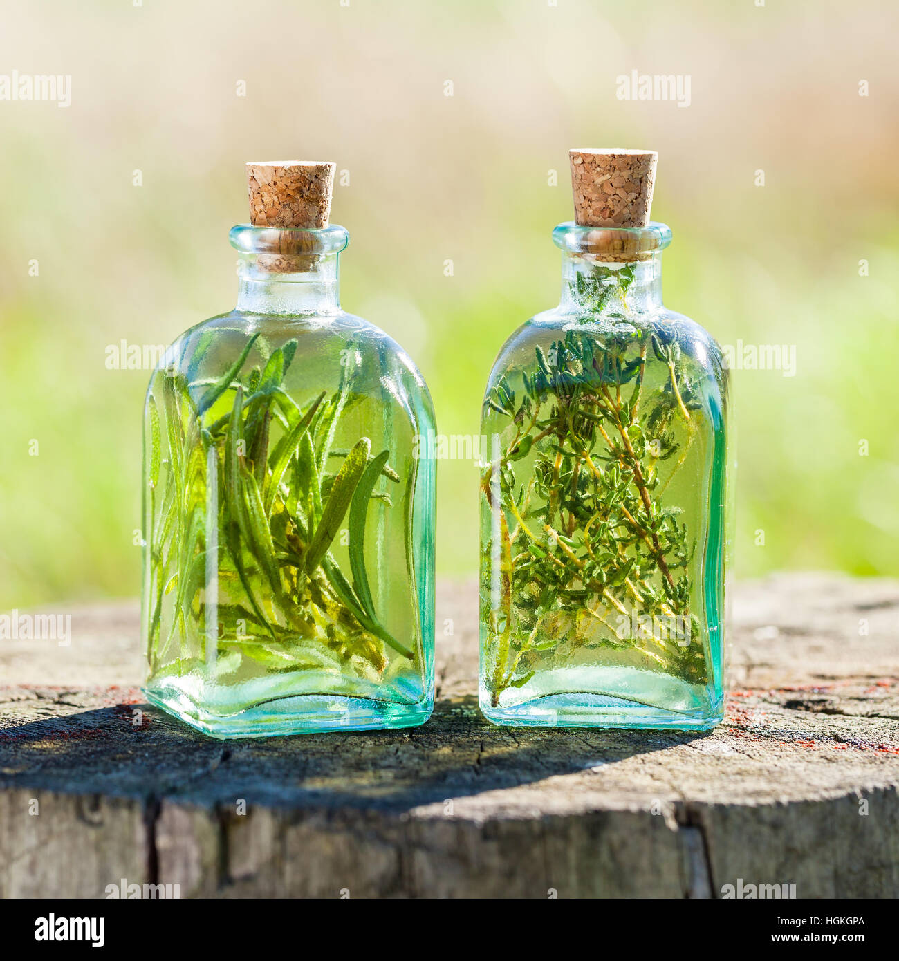 Bottles of thyme and rosemary essential oil or infusion outdoors