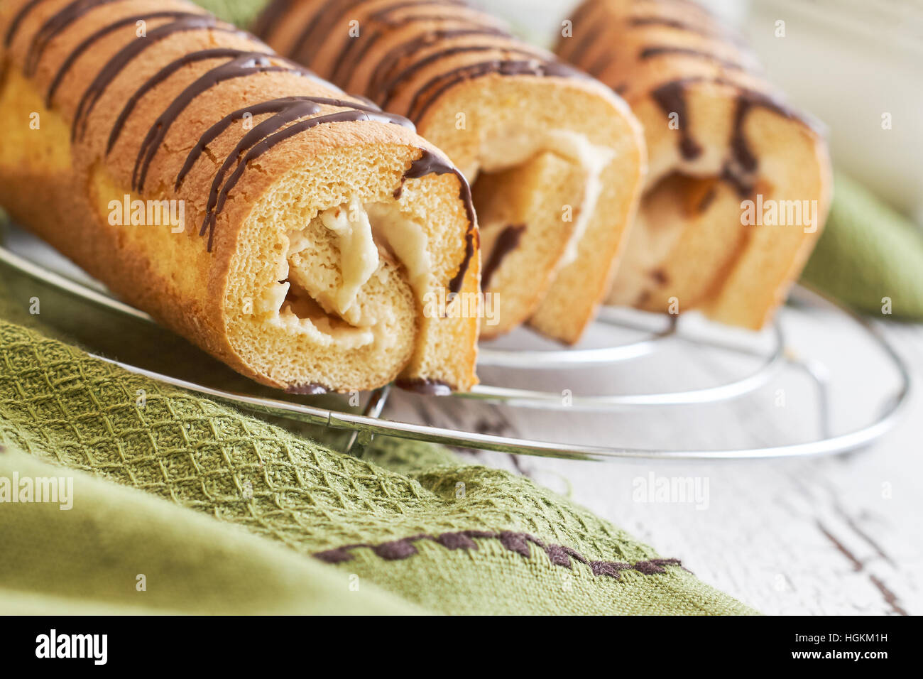 Sweet swiss rolls (roulade) with white cream on green tablecloth Stock Photo