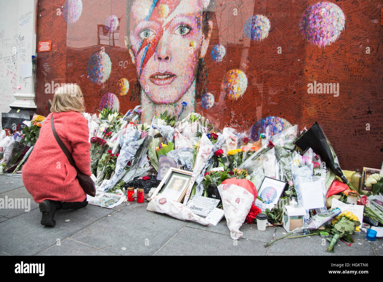 A fan lays flowers at the mural. Fans gather at the David Bowie mural ...