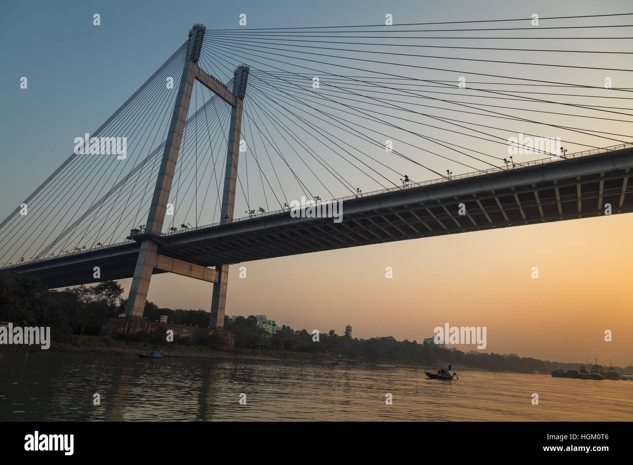 Vidyasagar bridge (setu) on river Hooghly at twilight . Wooden boats are used for pleasure trip on the river. Stock Photo