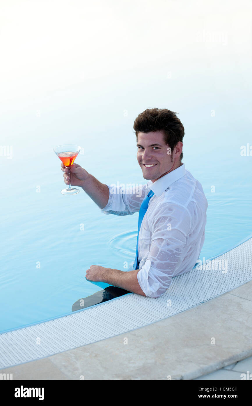 Attractive young man in the poo having a drink Stock Photo