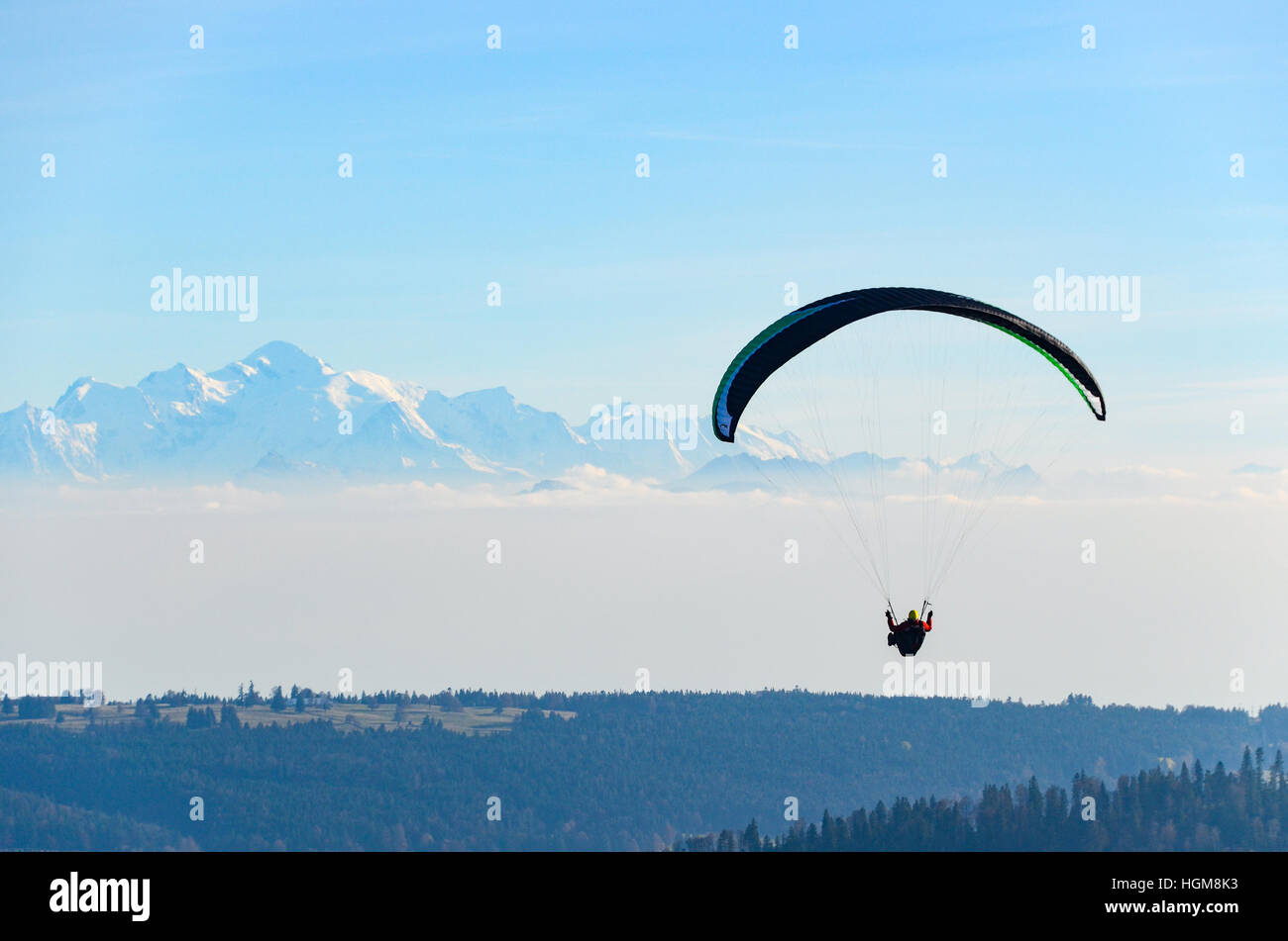 Paragliders flying over the Jura mountains with snowy Alps in the background Stock Photo
