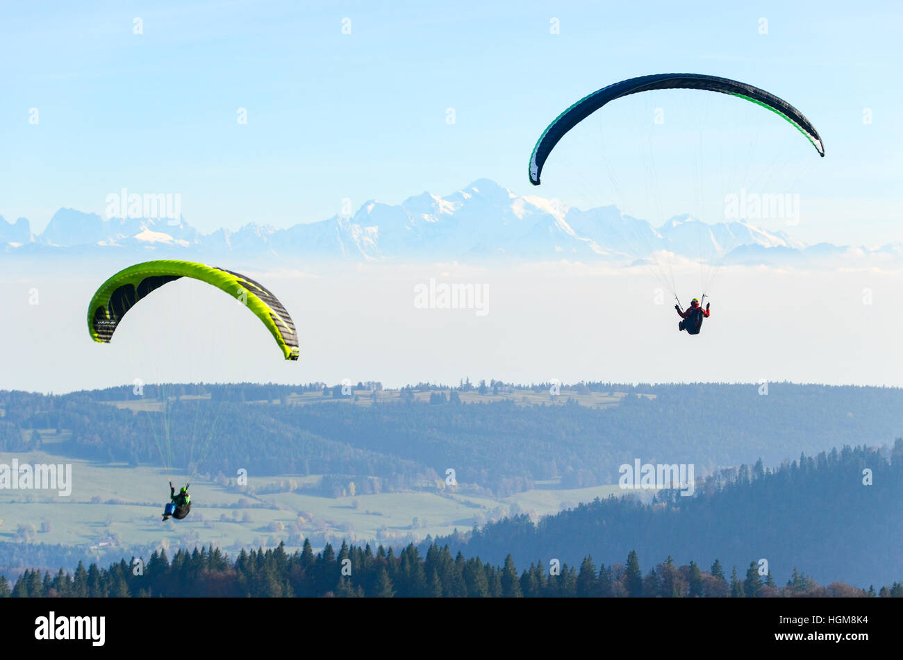 Paragliders flying over the Jura mountains with snowy Alps in the background Stock Photo