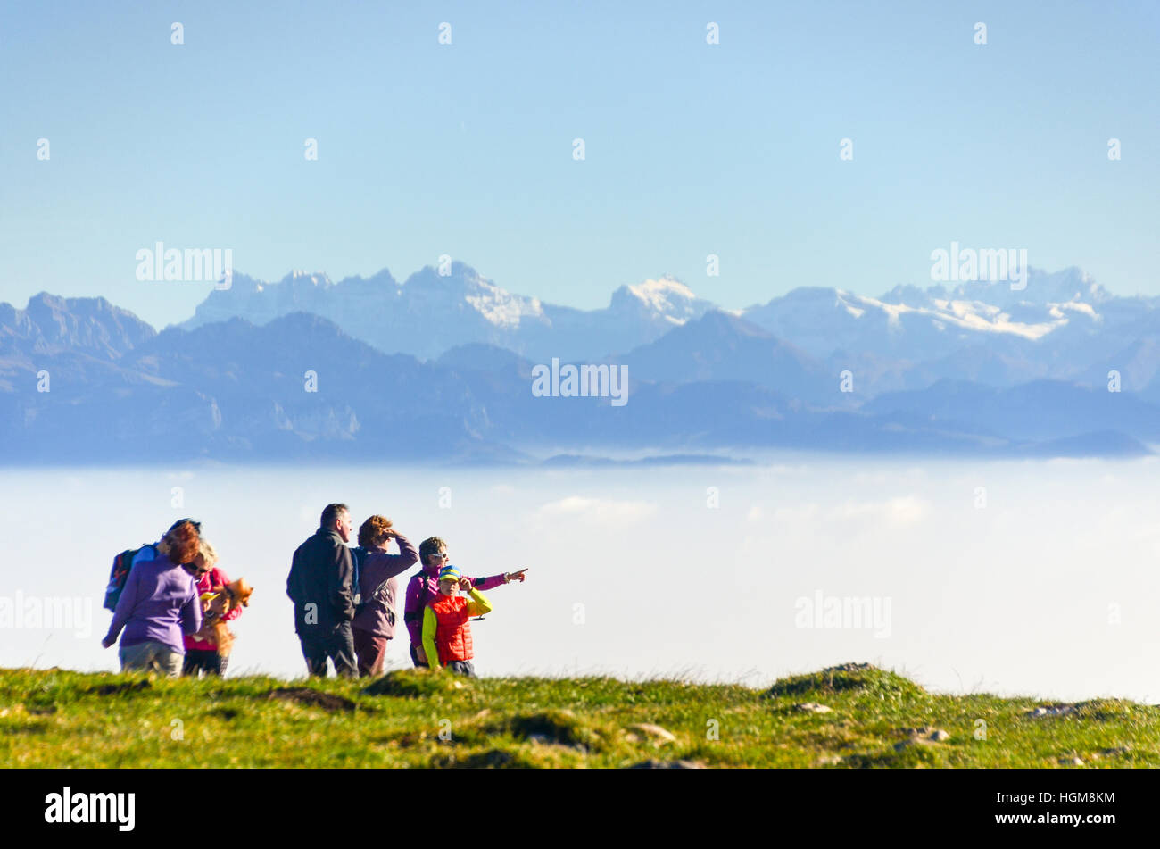Hikers pointing at the horizon in front of a panorama of the Swiss Alps seen from the Dent de Vaulion in the Jura Stock Photo