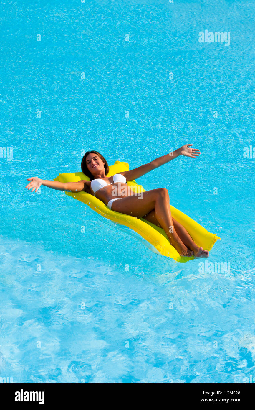 Happy Beautiful woman relaxing and floating on pool, high angle view Stock Photo