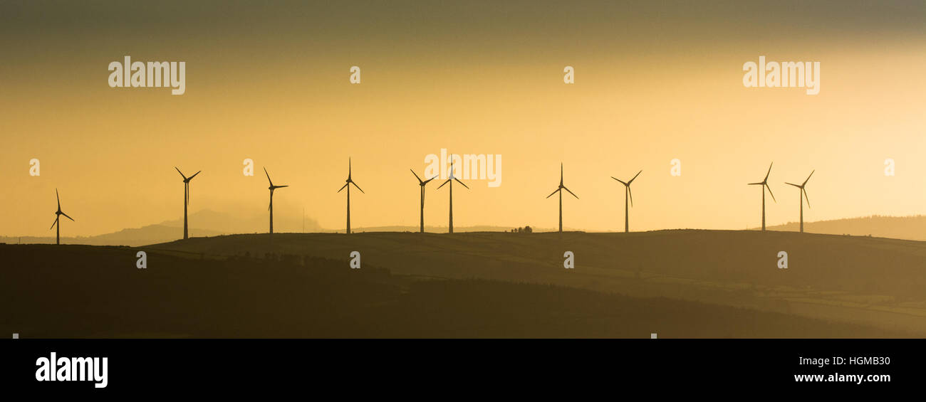 Giant wind turbines at golden hour along the ridge of a hill in the Blackstairs mountains in south east Ireland Stock Photo