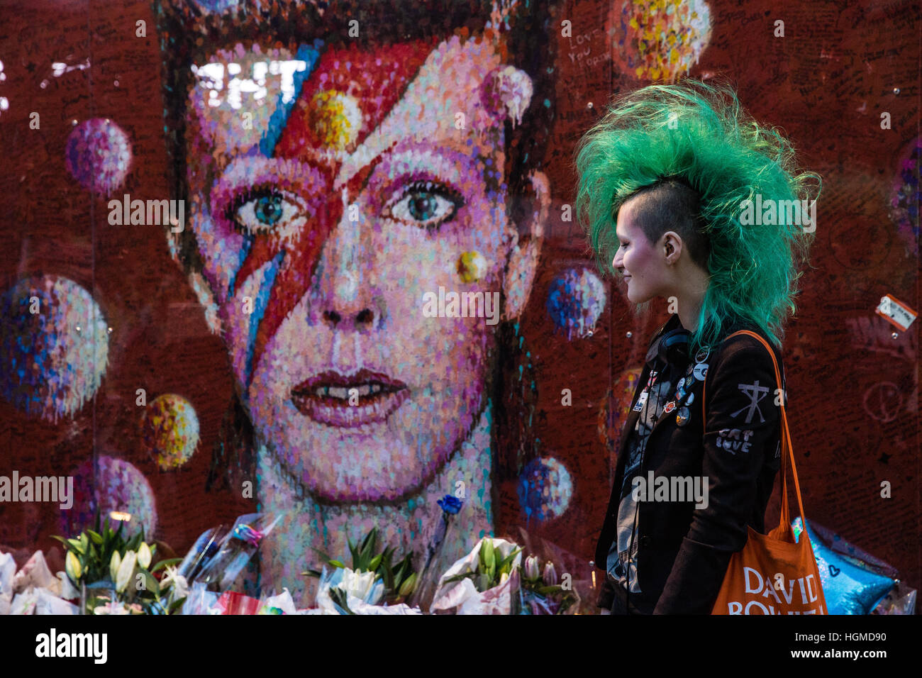 London, UK. 10th January, 2017.  A girl with a green mohican haircut pays tribute to David Bowie in front of a mural in Brixton on the first anniversary of his death. Credit: Mark Kerrison/Alamy Live News Stock Photo