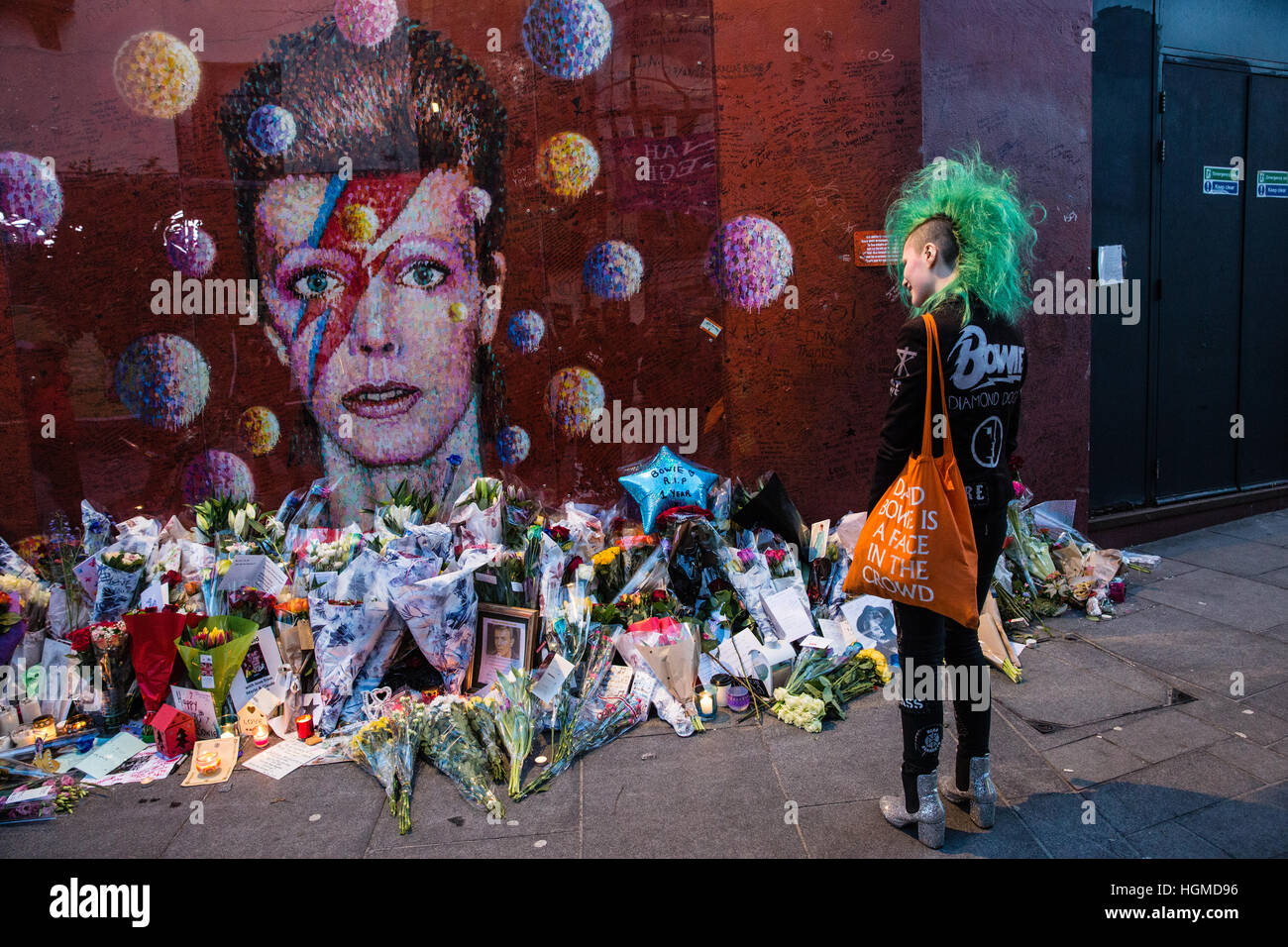 London, UK. 10th January, 2017.  A girl with a green mohican haircut pays tribute to David Bowie in front of a mural in Brixton on the first anniversary of his death. Credit: Mark Kerrison/Alamy Live News Stock Photo