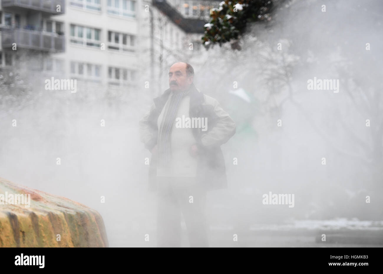 Wiesbaden, Germany. 11th Jan, 2017. Musa Adan from Wiesbaden is clouded in steam and fog at the 'Kochbrunnen' (lit. 'boil fountain') in Wiesbaden, Germany, 11 January 2017. The shell shaped fountain is a frequented site for people attuned to their health. The hot spring spews out thermal water at 68, 75 degrees, which is considered to hold beneficial effects for human health. Photo: Arne Dedert/dpa/Alamy Live News Stock Photo