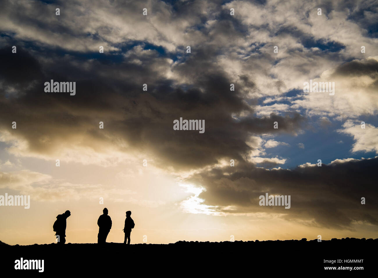 Aberystwyth Wales UK, Wednesday 11 Jan 2016  UK weather: A group of people walking along the Ceredigion section of the Wales Coastal Path  at Tanybwlch beach Aberystwyth, as the sun bursts through the clouds before the stormy, wet and possibly snowy weather sweeps down from the north overnight   photo © Keith Morris / Alamy Live News Stock Photo