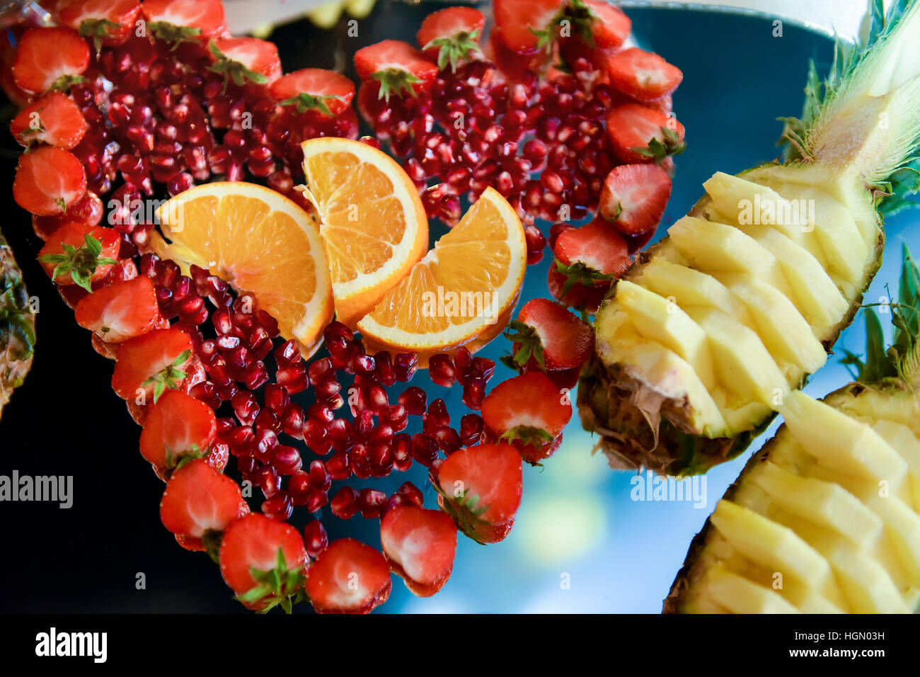 Arrangement with fruits: strawberries, pineapple, pomegranate, orange light side Stock Photo