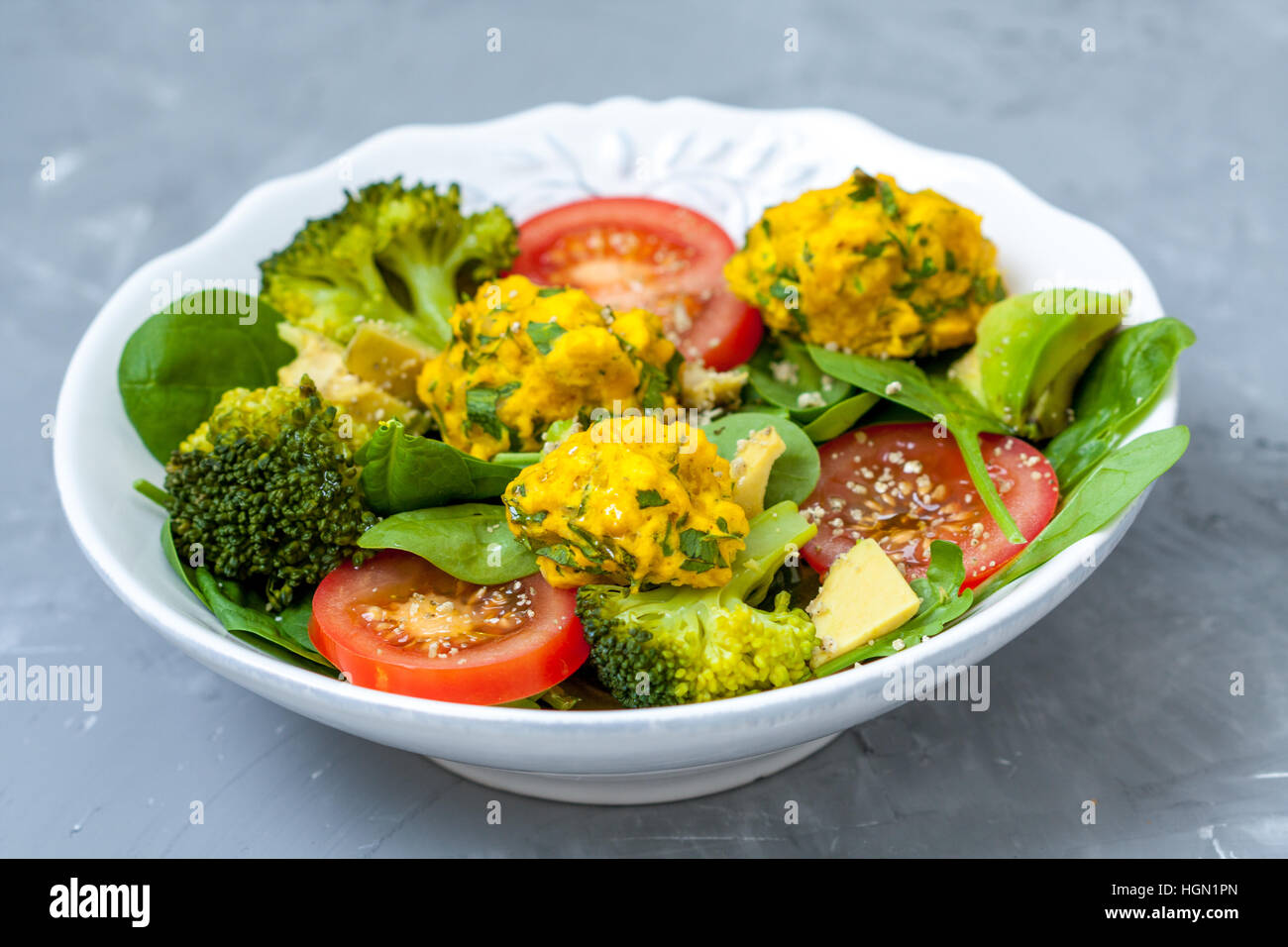 Spinach, lentil balls, avocado, tomatoes - vegan lunch. Healthy homemade vegan food content. Stock Photo
