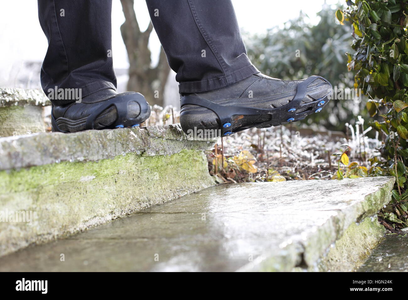 A Man with Shoe snow spikes in winter on icy stairs Stock Photo