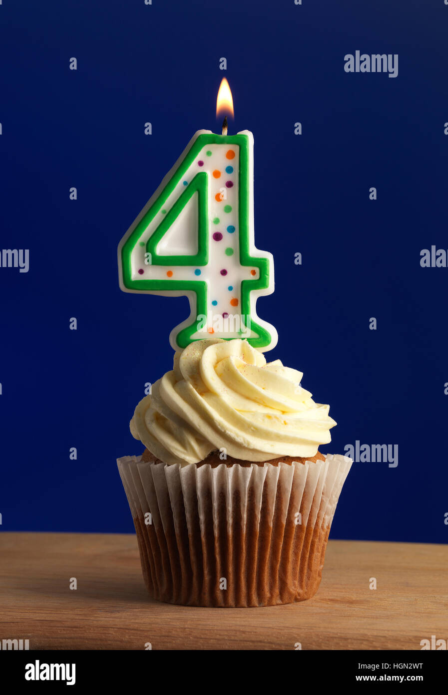 Cupcake with frosting and candle with number four and a Blue Background Stock Photo