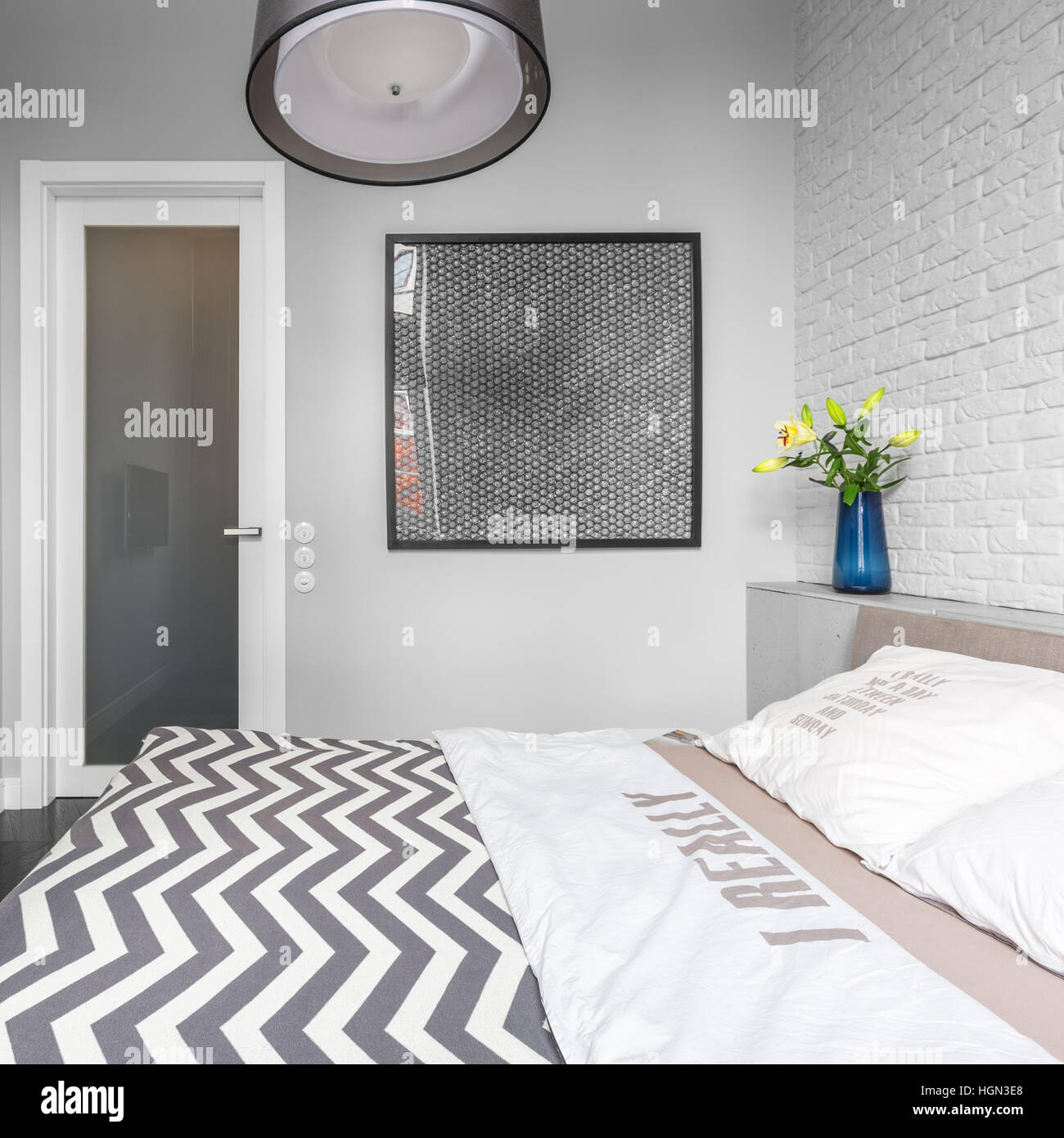 Grey bedroom with brick wall and double bed Stock Photo - Alamy