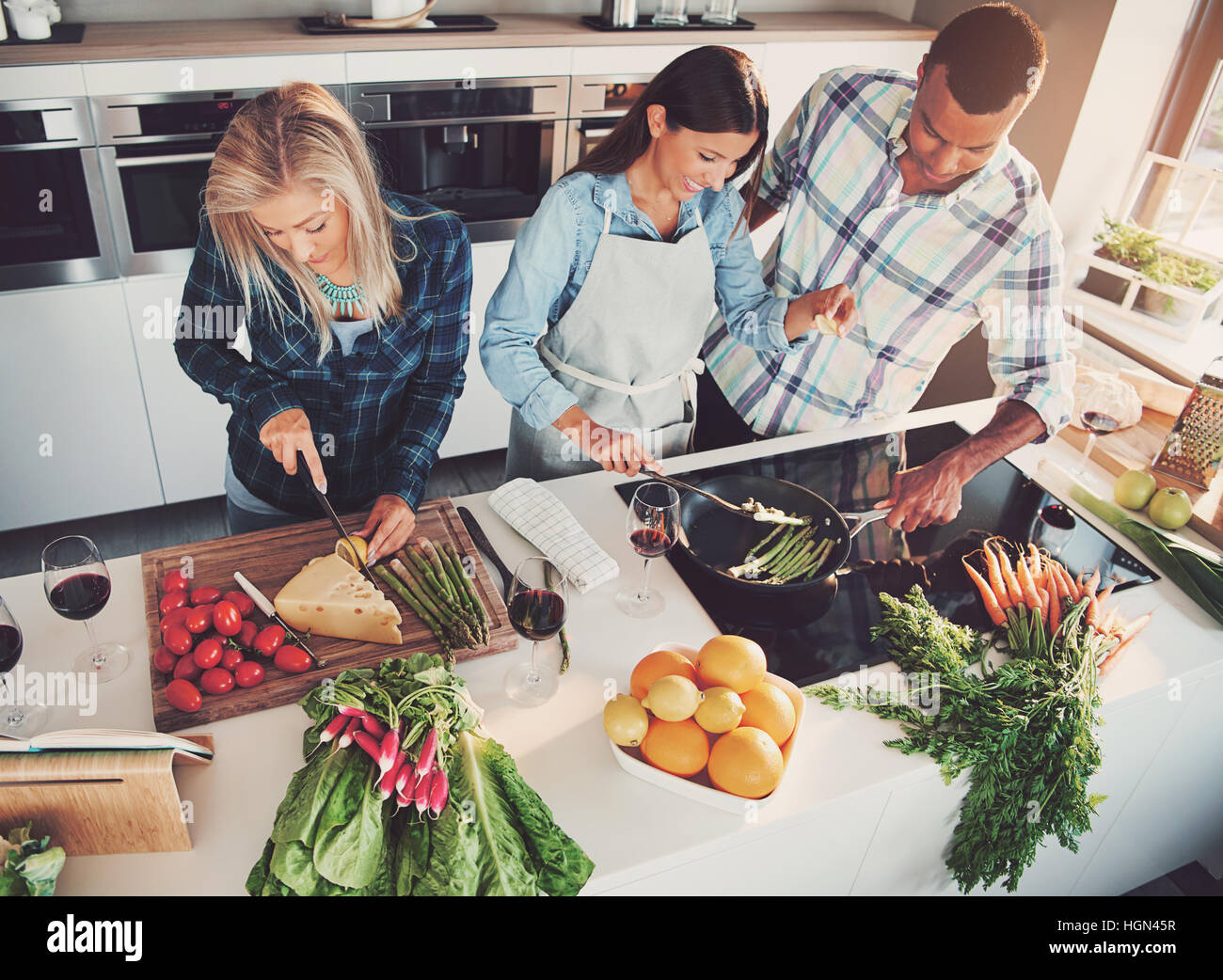 Three friends cooking at kitchen clearly having fun, shot from above Stock Photo