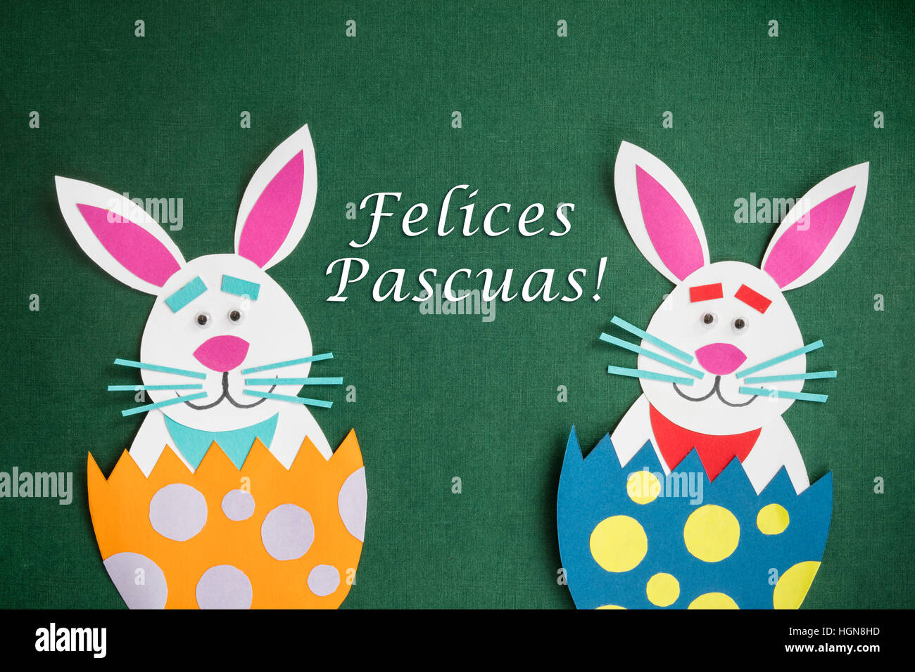 Funny handmade cartoon rabbits placed inside eggs and text in Spanish 'Felices Pascuas', which means 'Happy Easter holidays'. Stock Photo