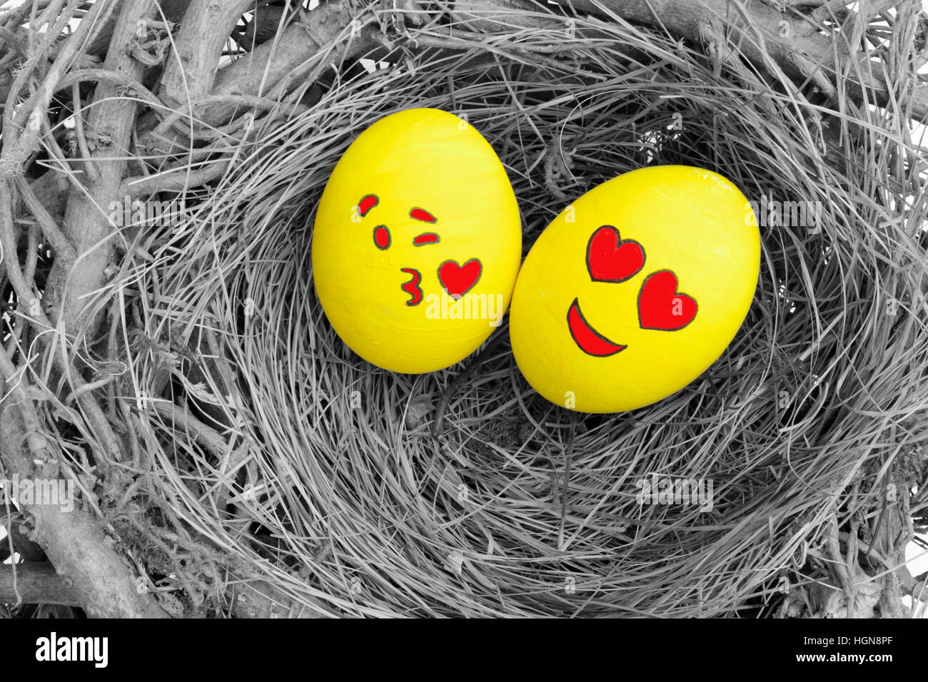 Two Easter eggs painted with emojis one in love and other kissing