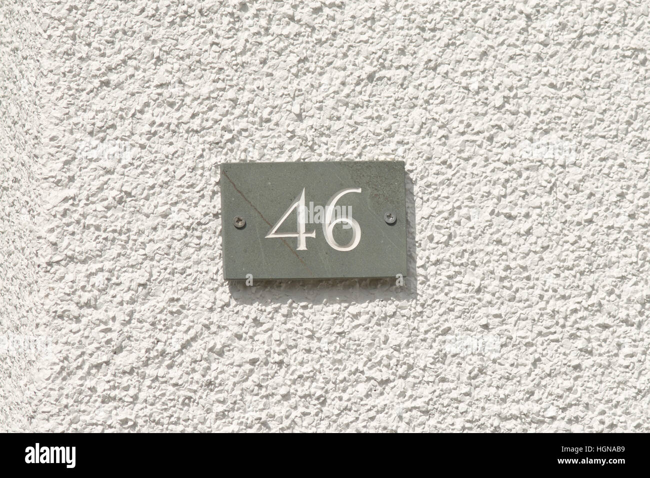 House Number 46 sign on wall painted white Stock Photo