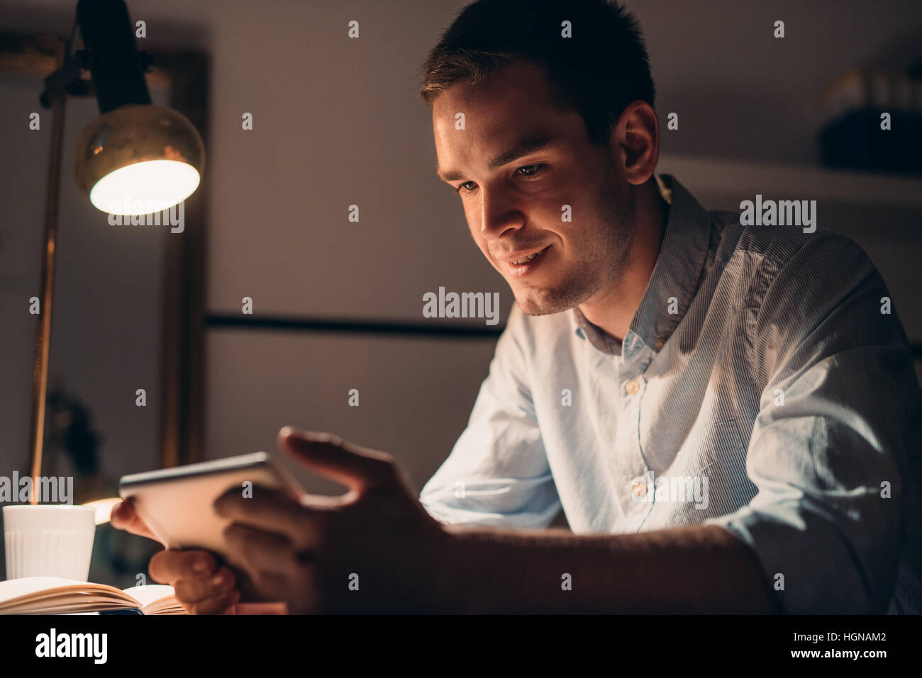 Smiling young businessman working using a tablet late at night Stock ...