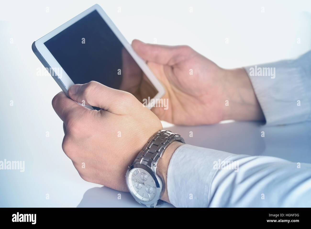 Tablet computer in male hands stained in blue. The original size of the tablet PC is changed. Stock Photo