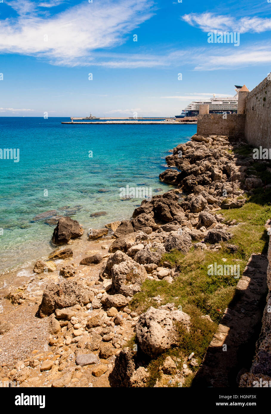 aegean sea with rhodes medieval wall leading to a moored ship in harbour Stock Photo