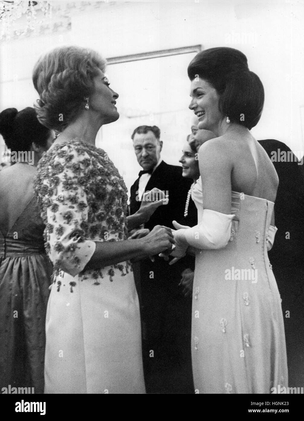 Madame Nicole Alphand, wife of Ambassador to the United States Hervé Alphand from France, left, and first lady Jacqueline Bouvier Kennedy, right, admire each other's gowns as they chatted together at a dinner party at the Embassy of France prior to the op Stock Photo
