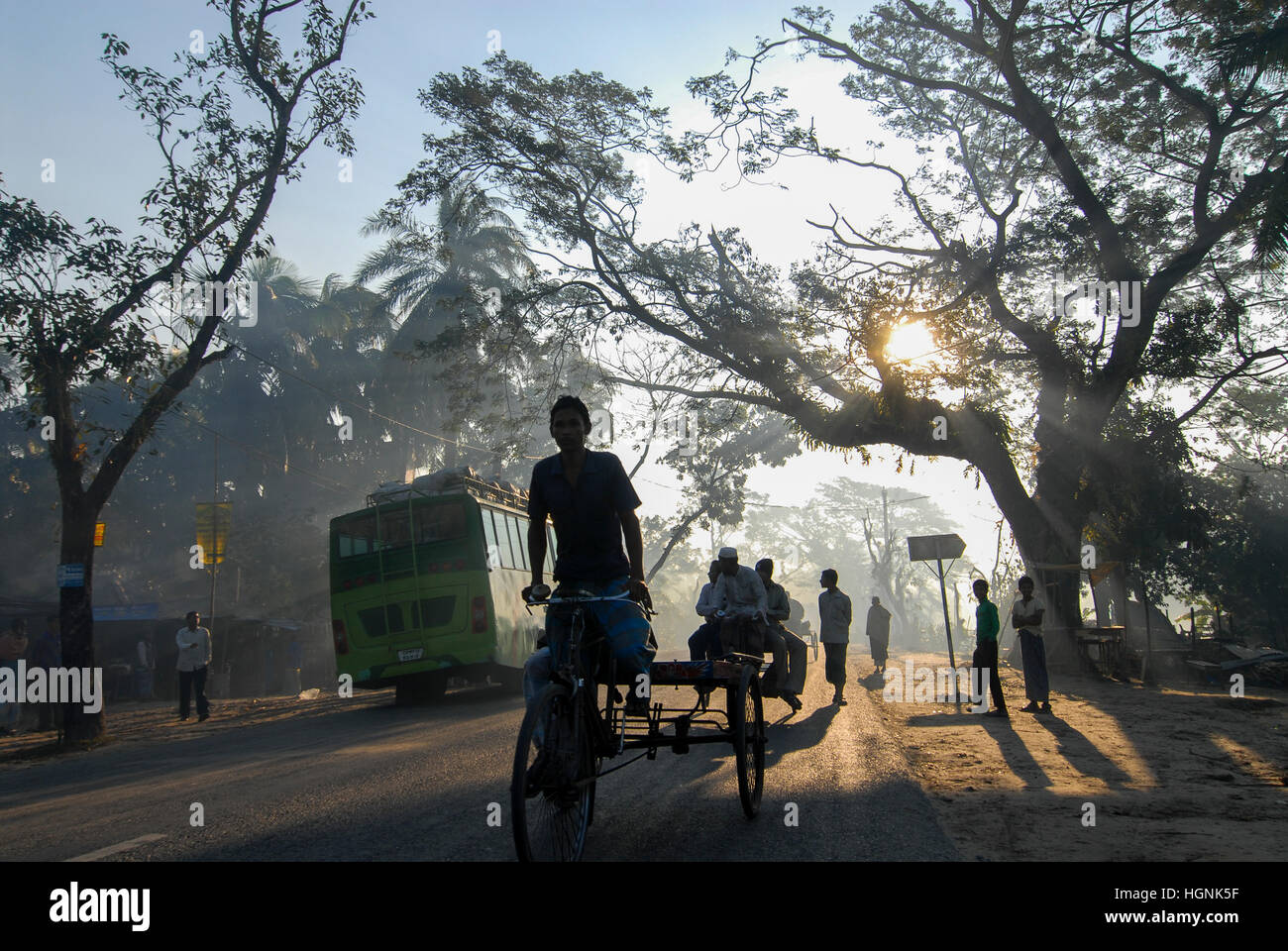 BANGLADESH, Khulna District, morning mist at road in village, Bus and bicycle rikshaw / BANGLADESCH Khulna , Menschen, Rikscha und Bus im Morgennebel auf einer Strasse in einem Dorf Stock Photo