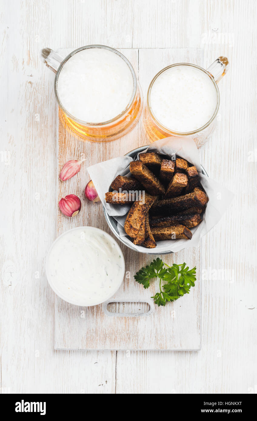 Beer snack set. Two mugs of pilsener, rye bread croutons, garlic cream